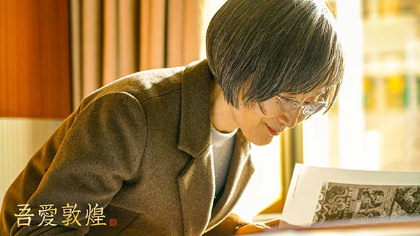 樊锦诗轻抚考古报告.jpg